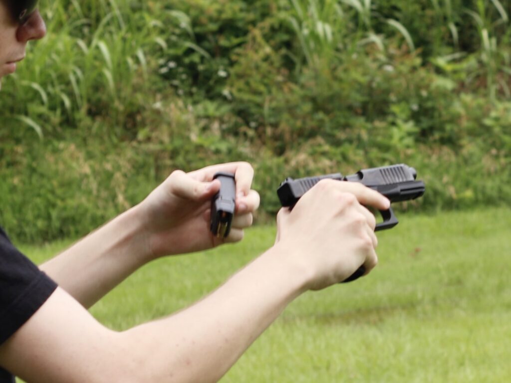 A forced malfunction drill done incorrectly — the shooter is holding the ejected magazine, leaving no free hand to clear the jam