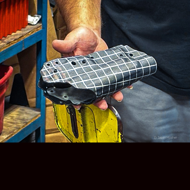 A person holding a black holster that has just been removed from the press.