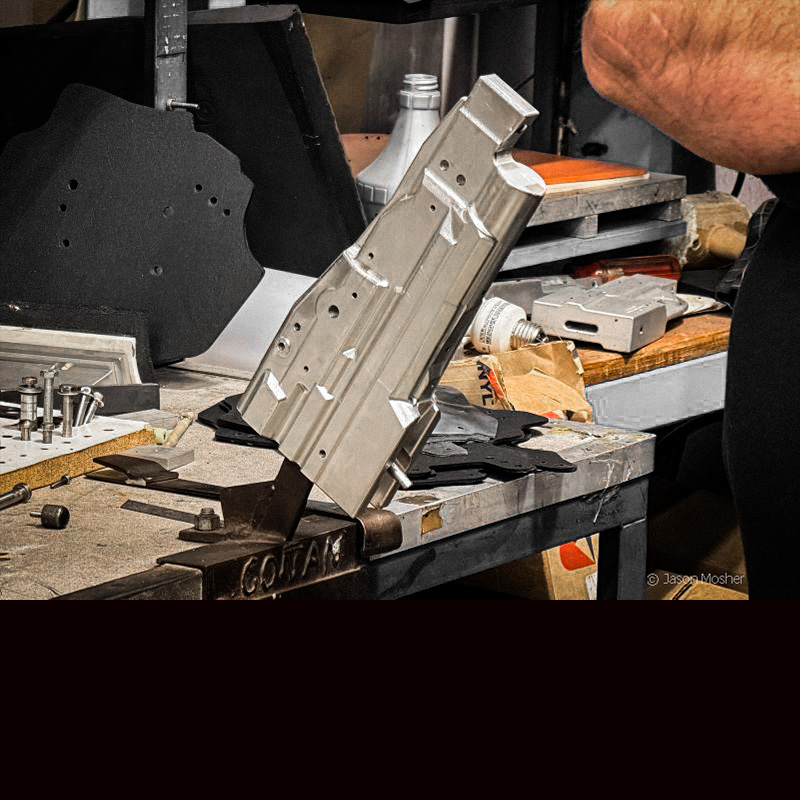 A silver, aluminum mold of a holster on a work bench.