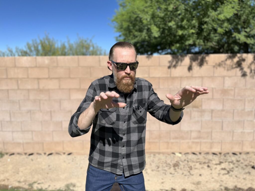 A man stands with his hands up in front of him for protection.