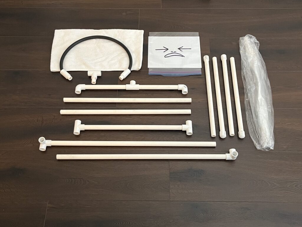 Several sections of white PVC pipe and other components required to make a Cellophane Man training aid are laid out on a brown plank floor.