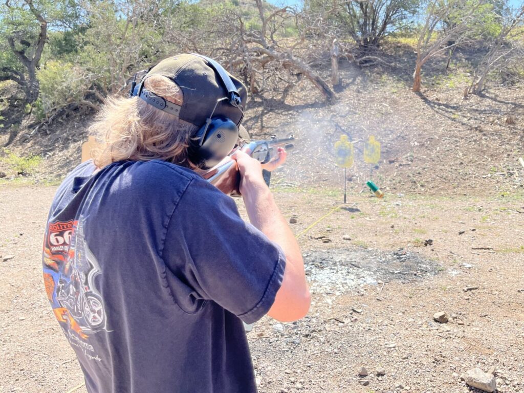 A student in a dark T-shirt shoots a Remington 1100 at one of two steel targets, after moving laterally to get a clear line-of-fire.