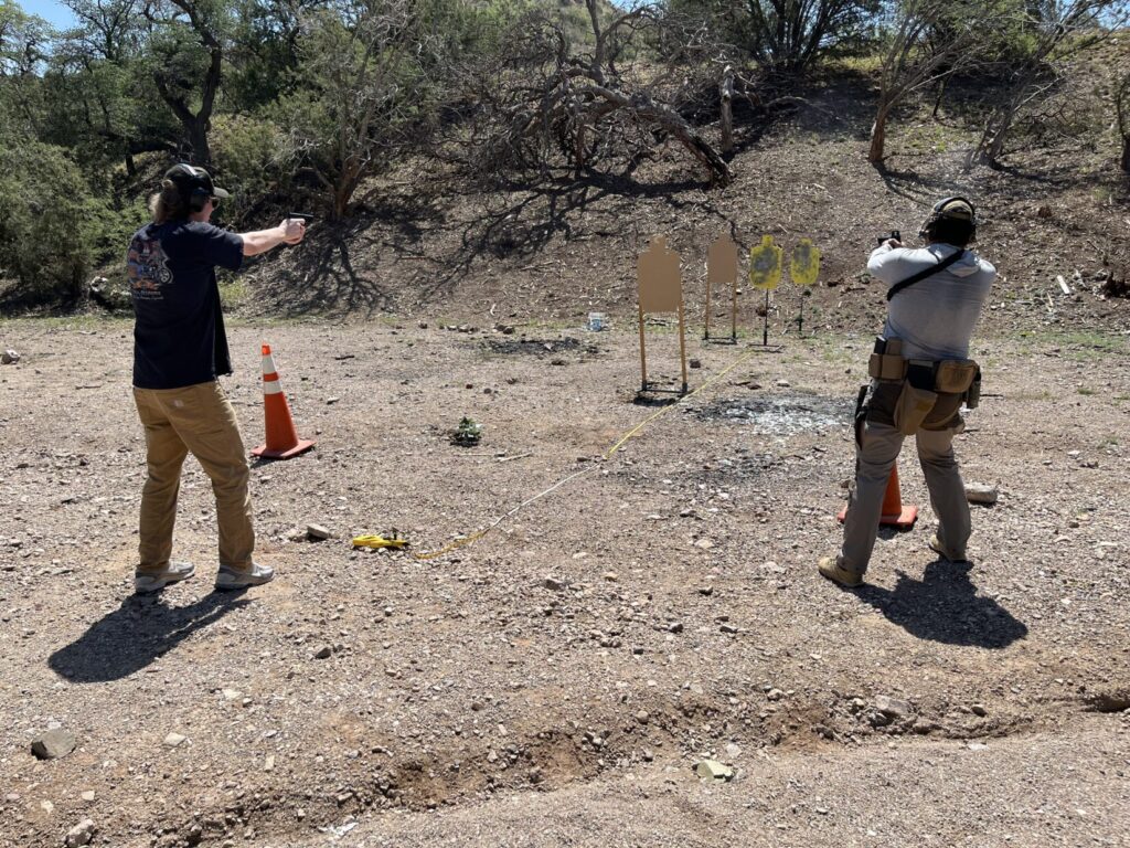 Two shooters face and array of four targets. The threat target is closer than the group of bystander targets behind it. The bystanders are in line with the threat from the shooter on the left. The shooter on the right has moved far enough right to get a clear line of fire.