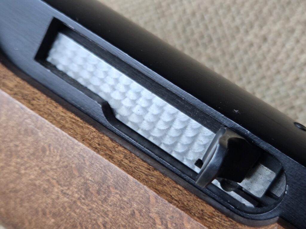 A rifle bolt and receiver against a burlap backdrop