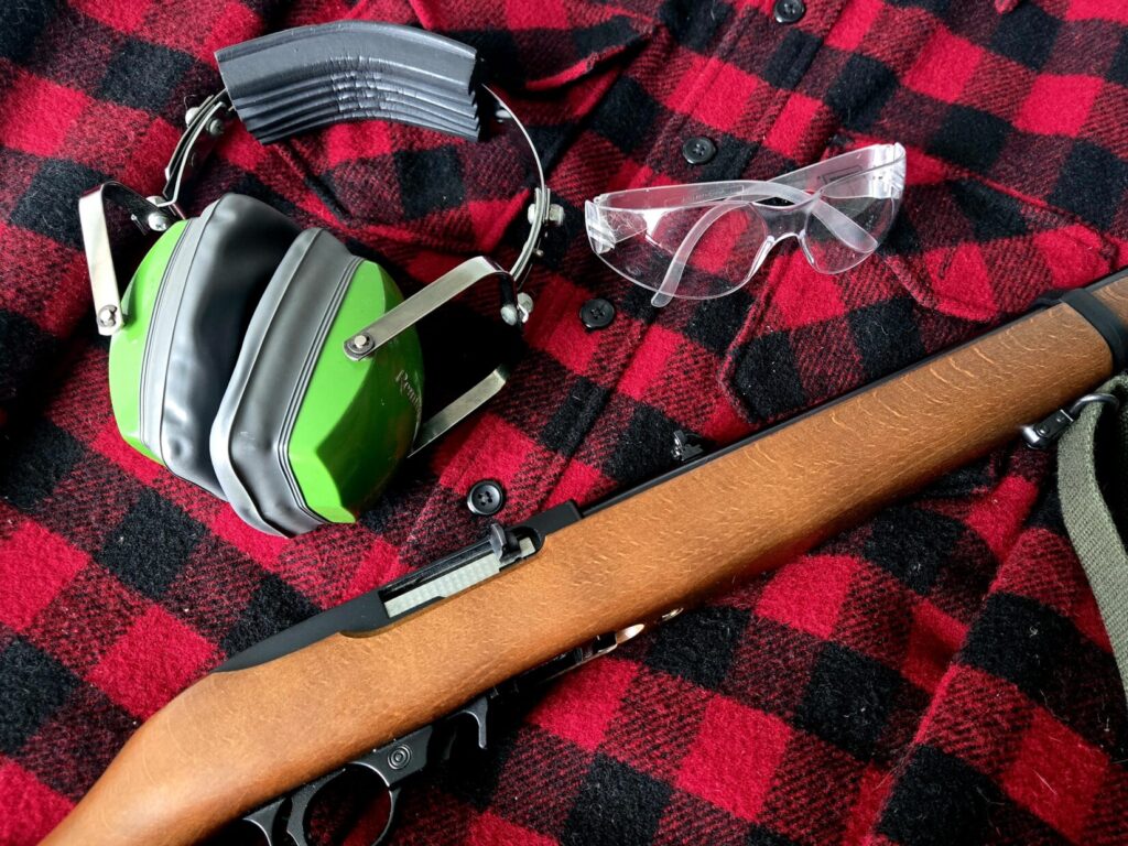 A 22 rifle ear and eye pro on top of a red flannel shirt