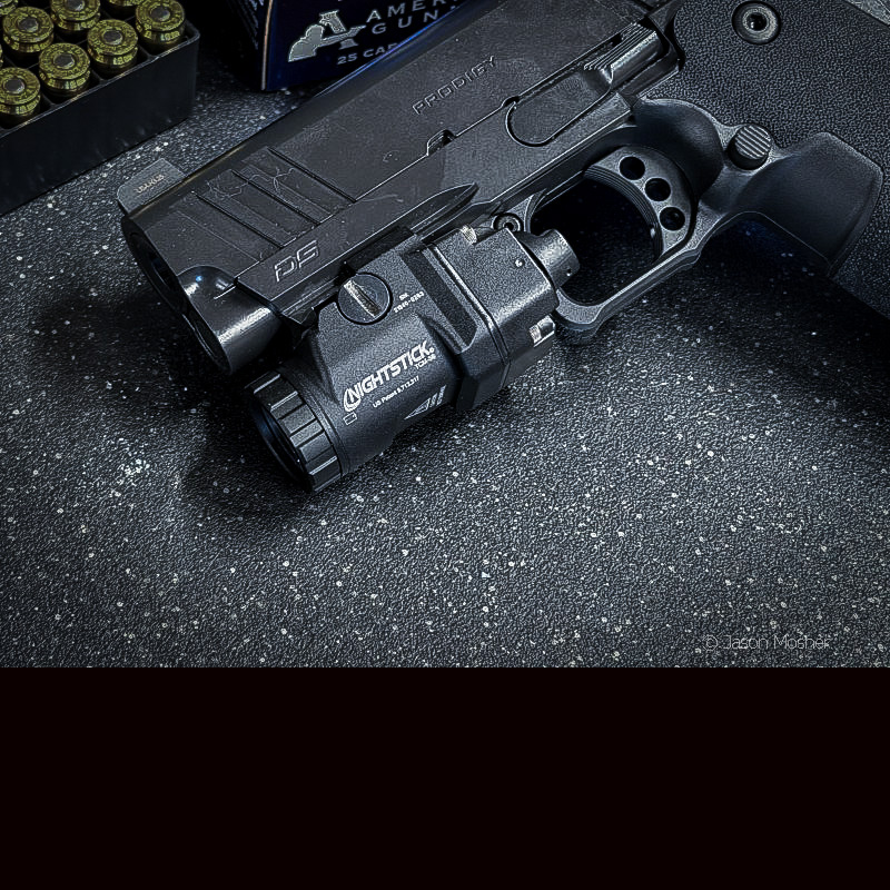 A close up view of a black Nightstick light mounted to the Prodigy 1911 handgun.