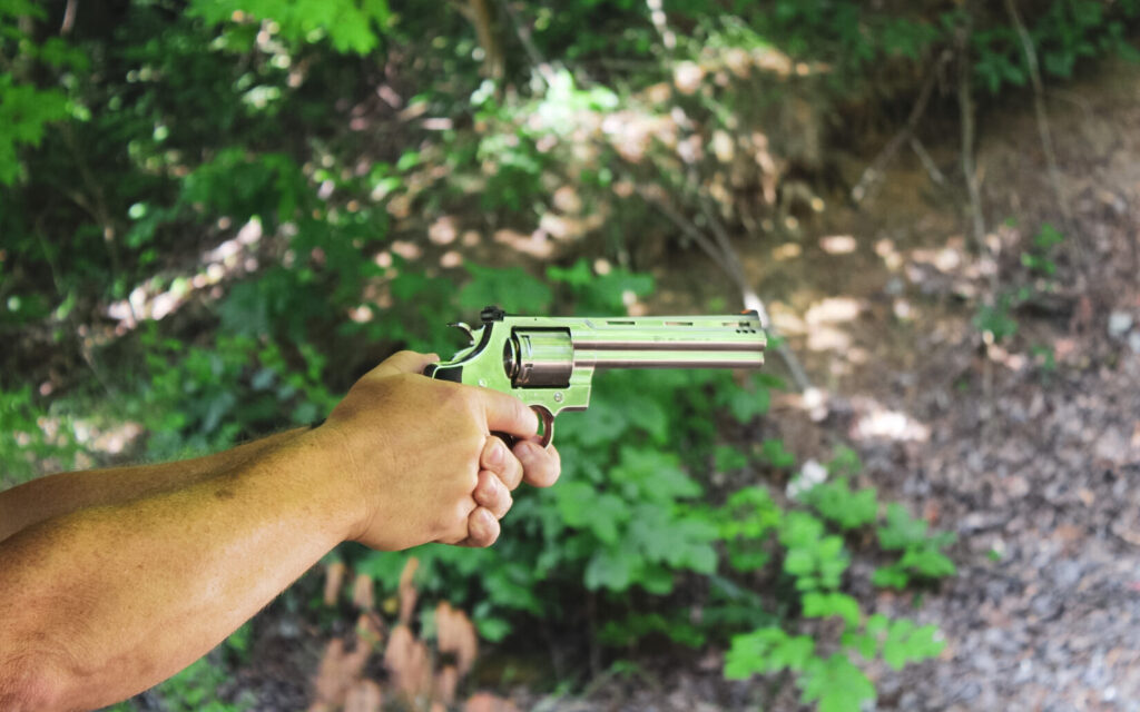 Man holding a revolver in nature.