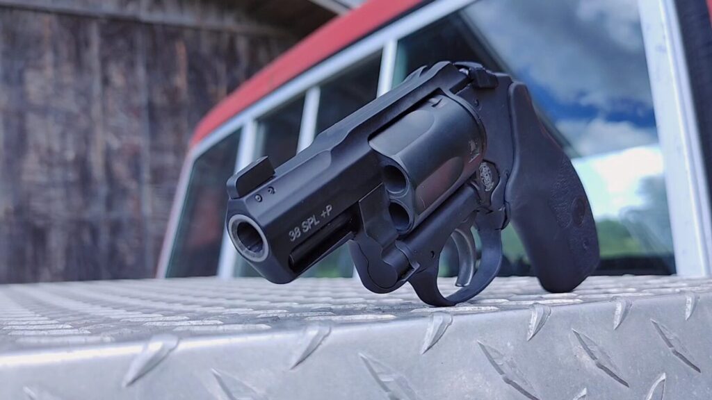 A low-angle, front-focused view of the revolver's muzzle and cylinder face, sitting on a silver diamond-plate metal toolbox.