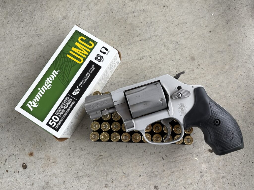 a smith & wesson j-frame sitting on a box of remington ammo