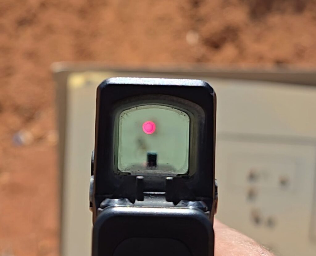 A pistol red dot aimed in at the small box in the top right of a target