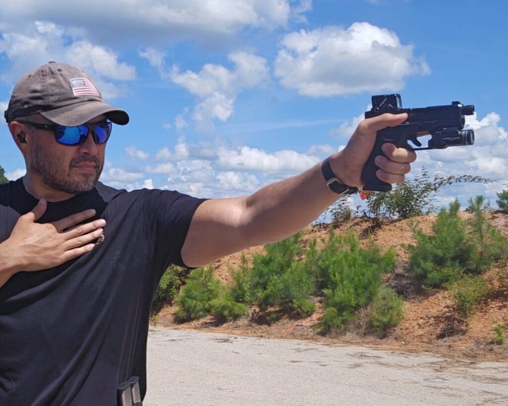A man in a black shirt shooting a pistol with his left hand.