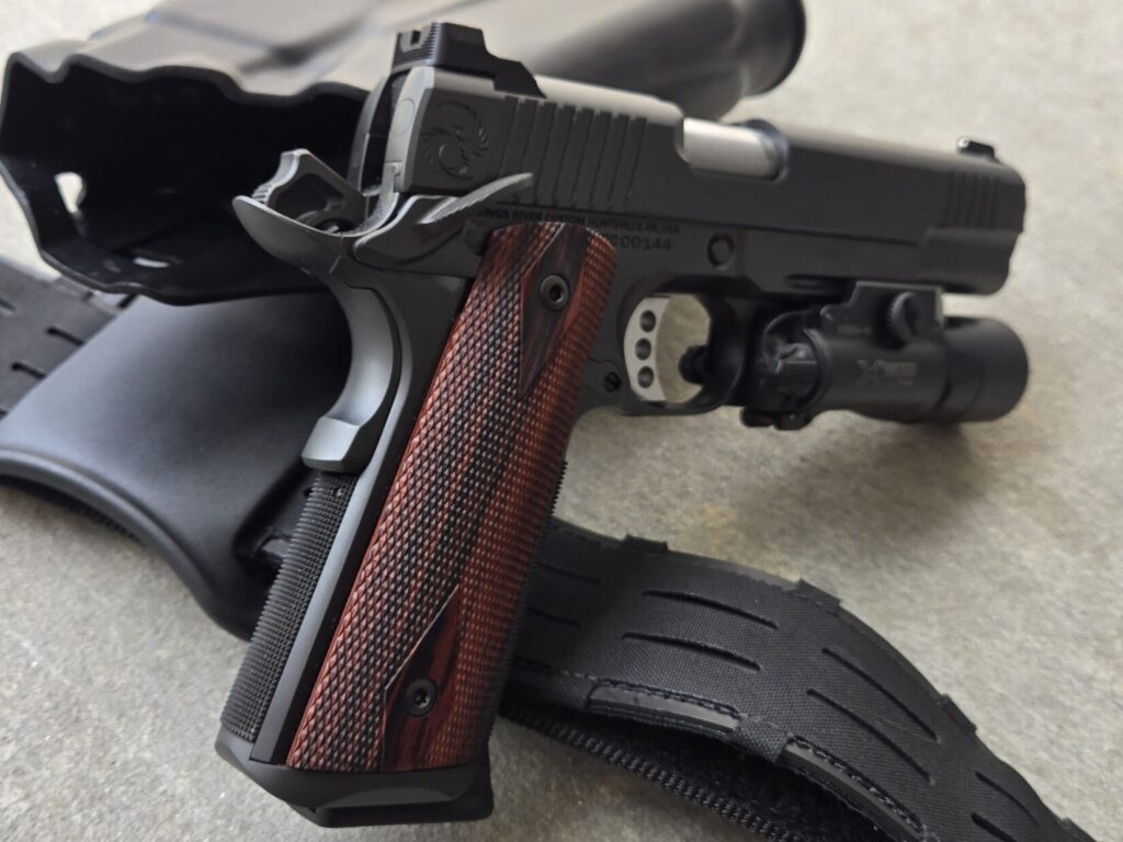 A 1911 pistol, pistol belt, and holster on concrete