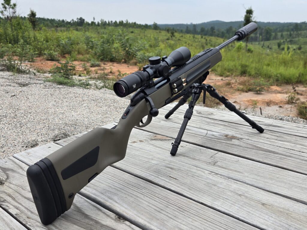 A Steyr rifle with suppressor, optic, and spare rounds carrier on a tripod