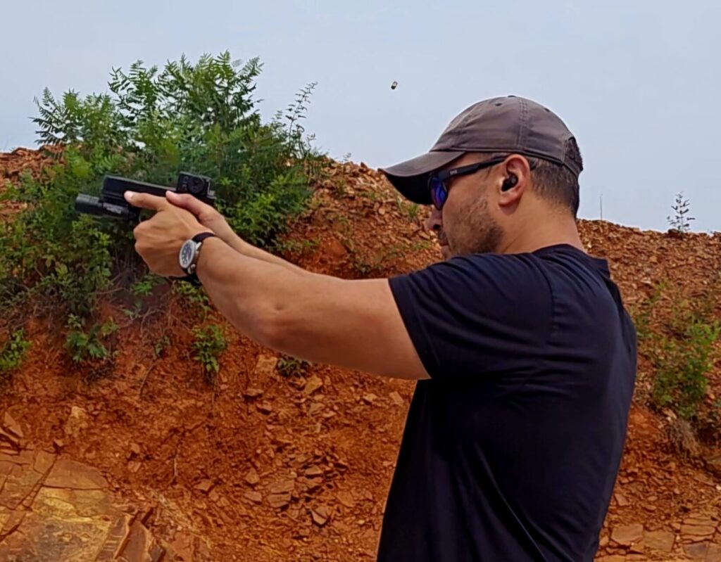 Kevin Estela firing a pistol at 25 yards with a two-hand grip as spent brass ejects