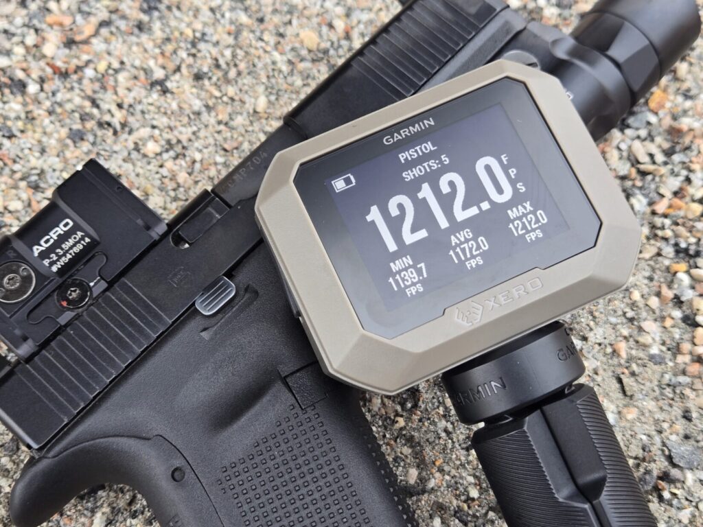 A chronograph set up next to a Glock pistol with a red dot sight for measuring muzzle velocity