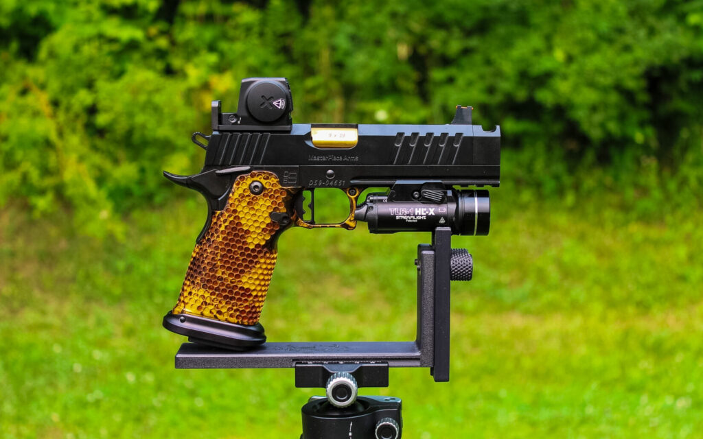 The MasterPiece Arms DS9-TC Hybrid in black and gold, mounted on a rest