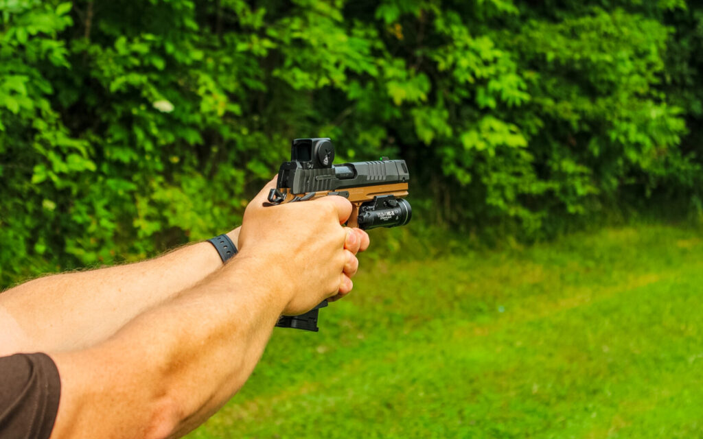 A man holding a black and brown pistol on a natural background.