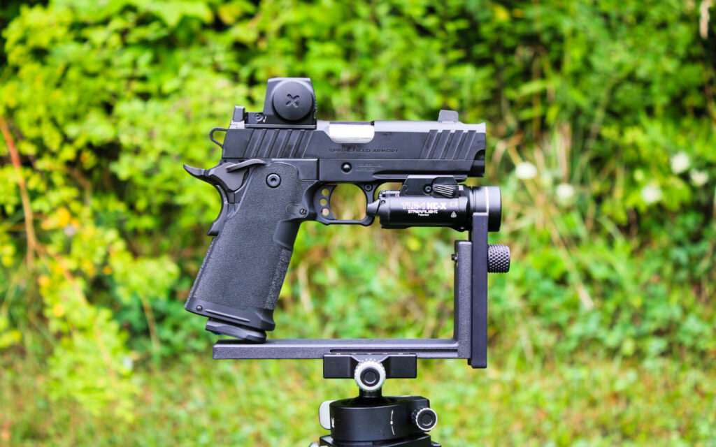 The Springfield Prodigy 4.25-inch Comp mounted in a rest with a Vortex red dot and Streamlight weapon light