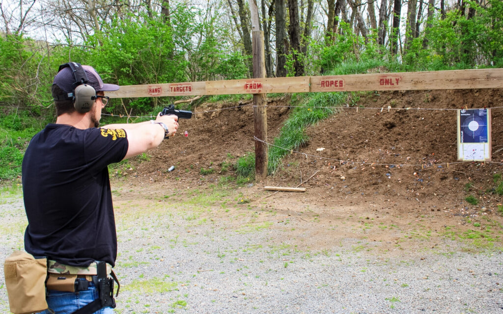 Man in a black shirt shooting a pistol.