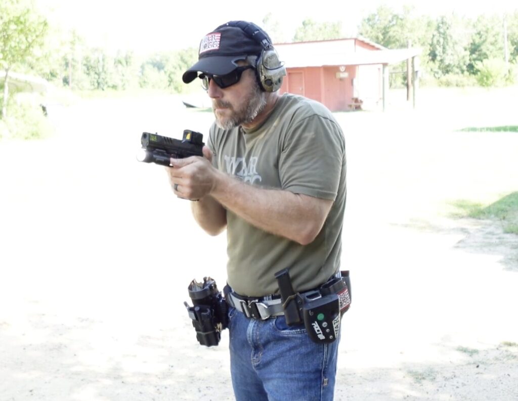 Close-up of Rick Hogg activating a pistol mounted light switch mid-draw during live fire training