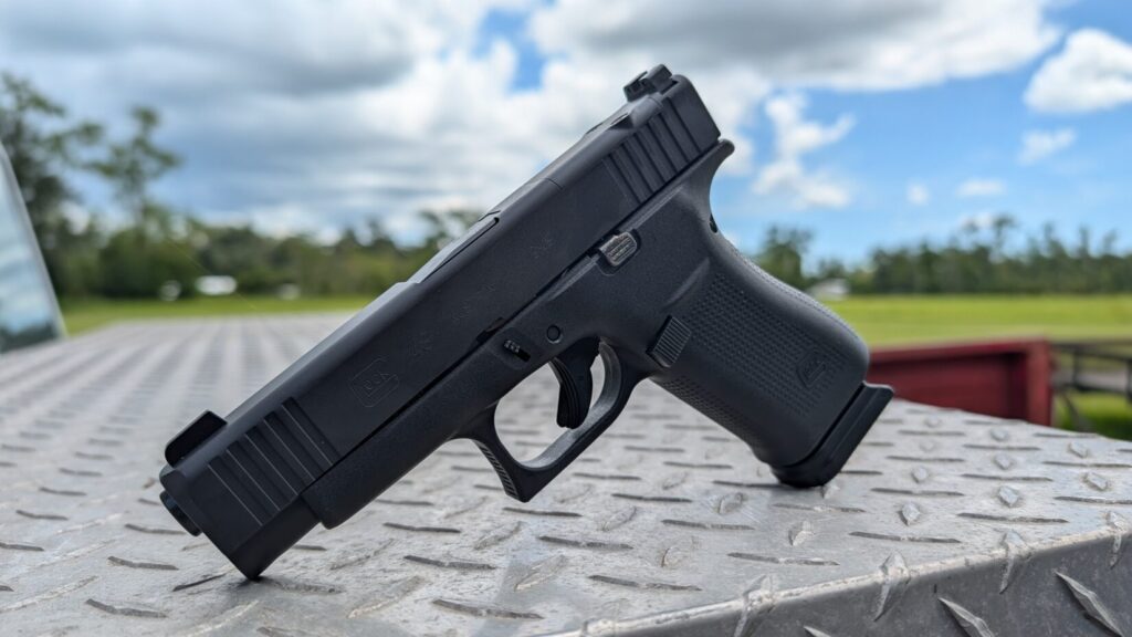 Loaded 15-round Glock magazine standing in front of a Glock 48 on a truck bed tailgate.