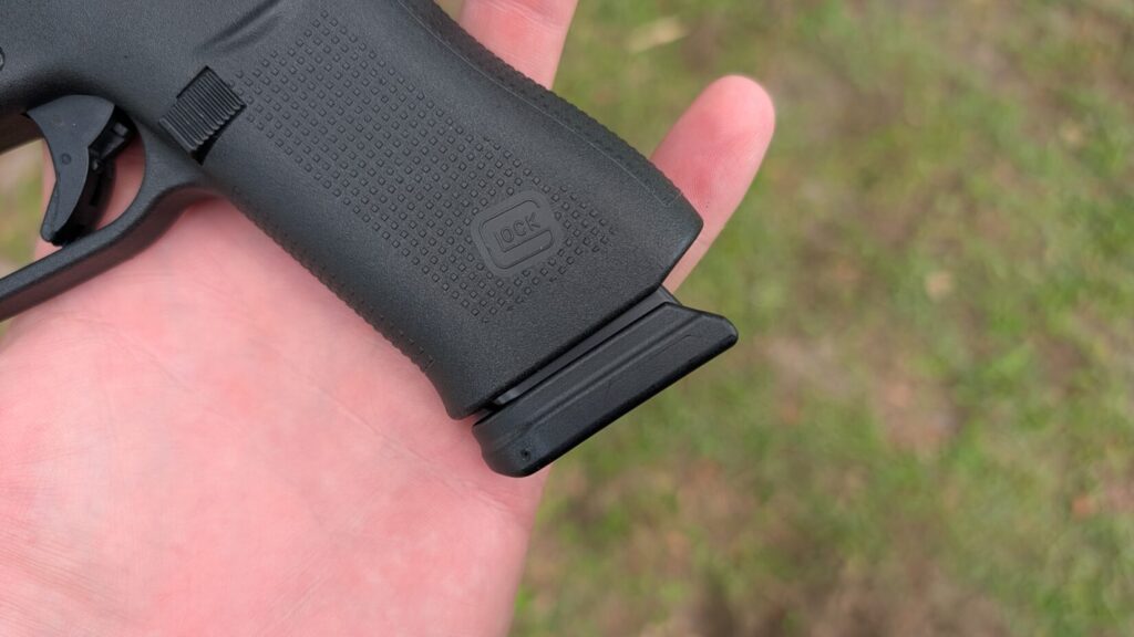 Hand holding the lower grip of a Glock 48, showing the magazine baseplate extension.