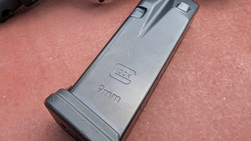 Close-up of a black 9mm Glock magazine body stamped with the Glock logo.