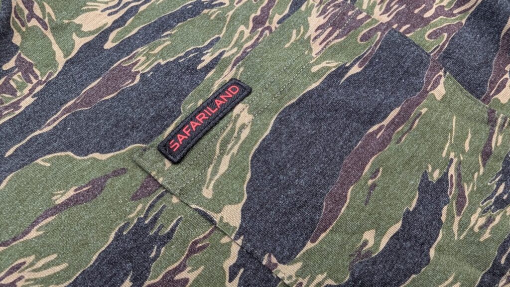 Close-up of the chest pocket on the tiger stripe camo hoodie featuring a red Safariland brand tag.