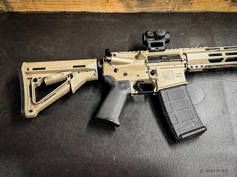 Tan Diamondback DB15 rifle on a black surface showing the tan stock and black pistol grip