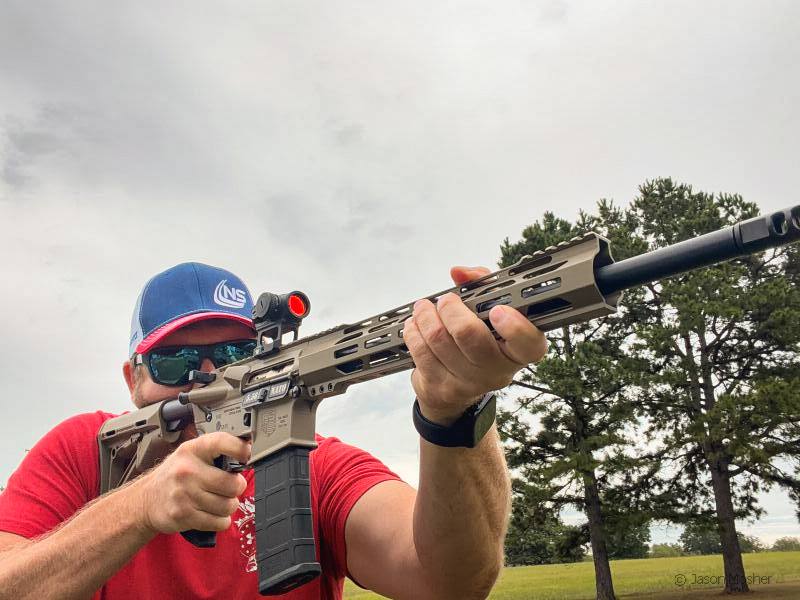 A person in a red shirt, shooting the Diamondback DB15 on the range.