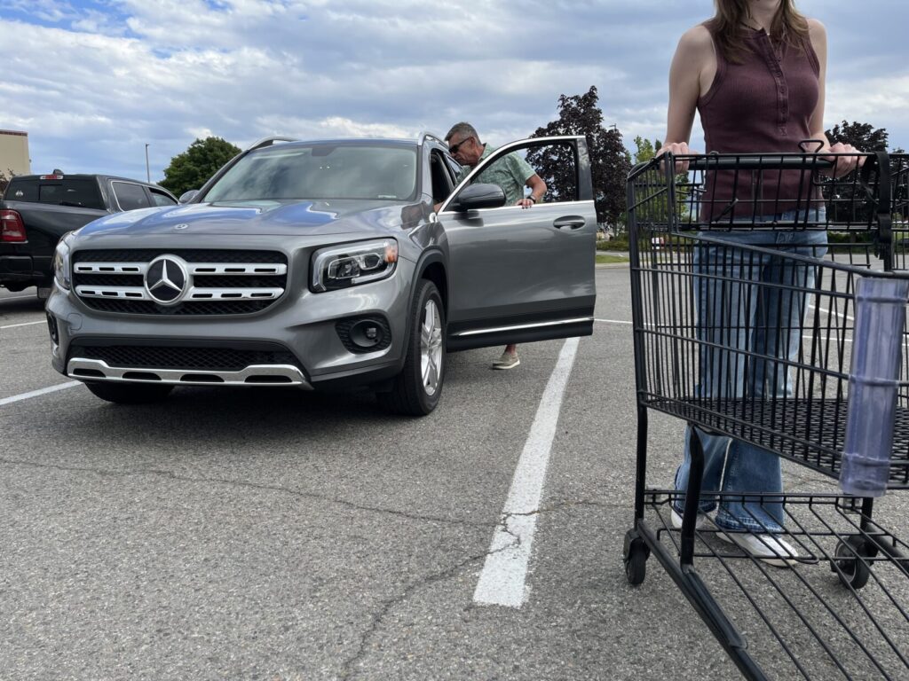 Image of a woman pushing a shopping cart toward the cart corral, while a man jumps into her driver's seat.