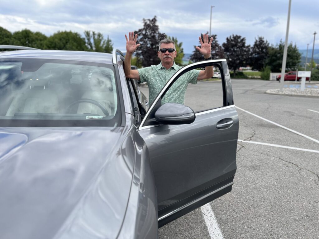 Image of a man representing a carjacker having just stepped out of the driver's seat, with his hands up.