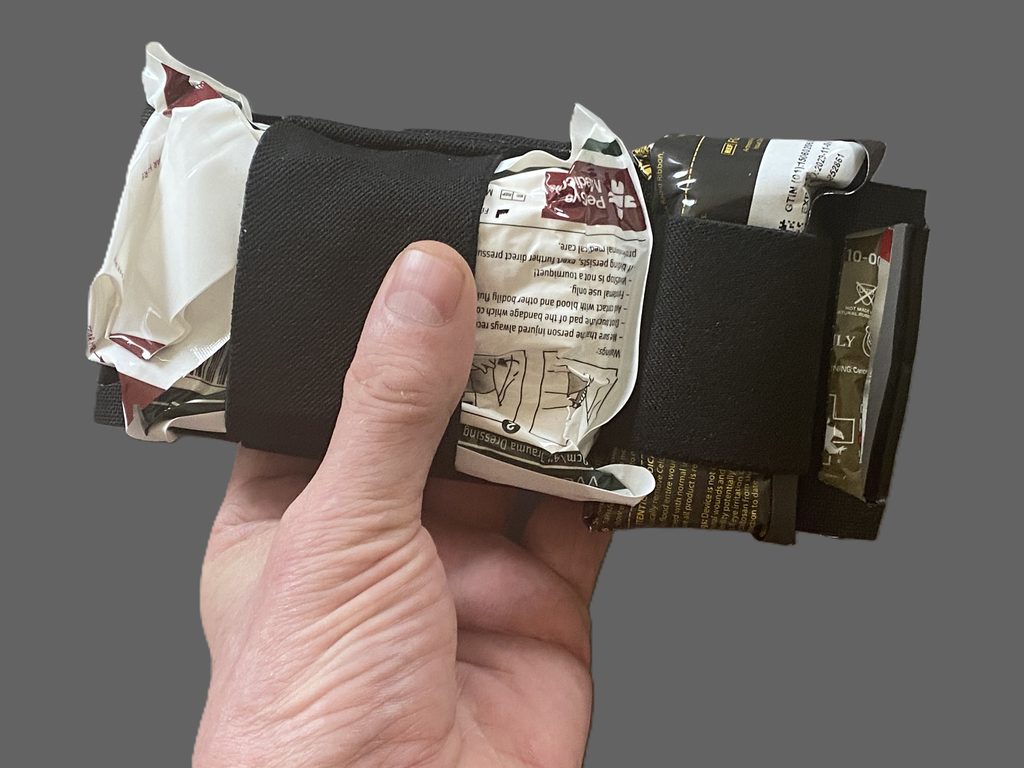 The ITRK's pull-out medical tray with hemostatic gauze, a chest seal, a pressure bandage, and an NPA held by wide elastic bands