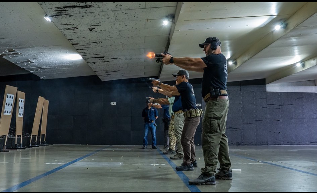 A well-lit indoor range shot showing a student's muzzle flash, illustrating how much brighter this same flash would appear in low light