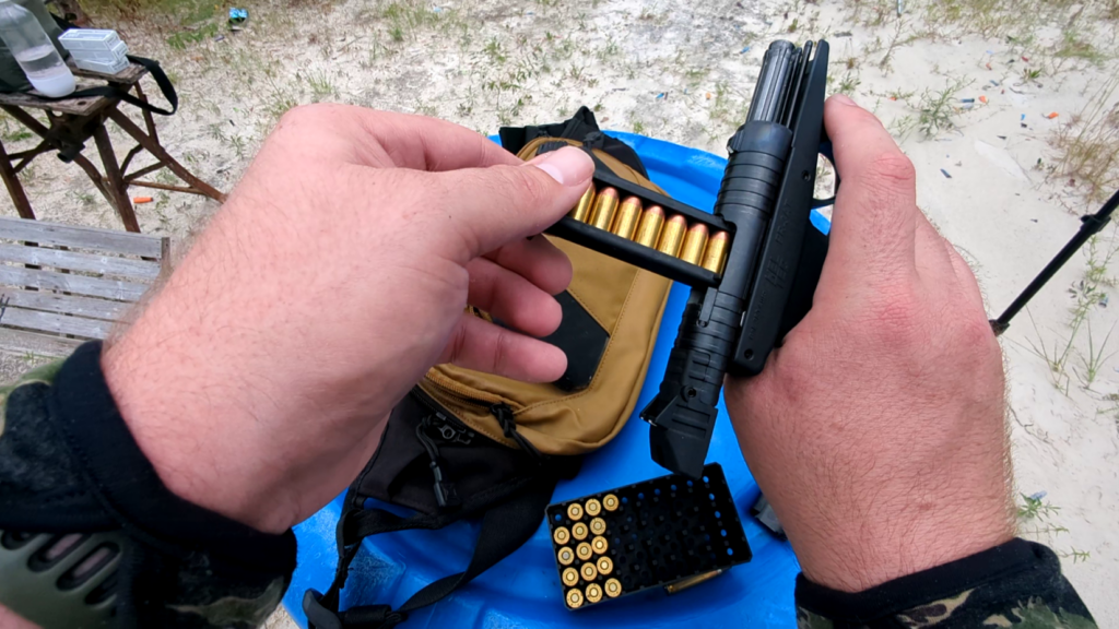 First-person view of a person inserting a loaded magazine into the top of an open PR-3AT pistol.