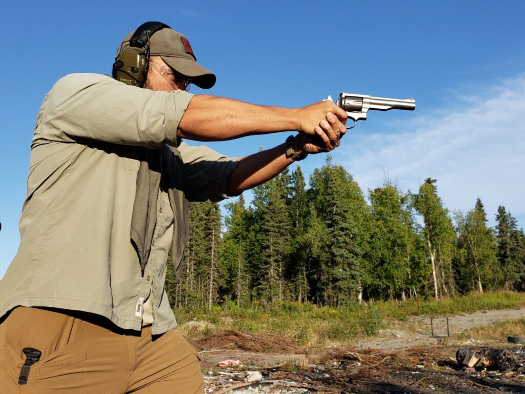 Kevin Estela aiming a revolver at an improvised range in Alaska