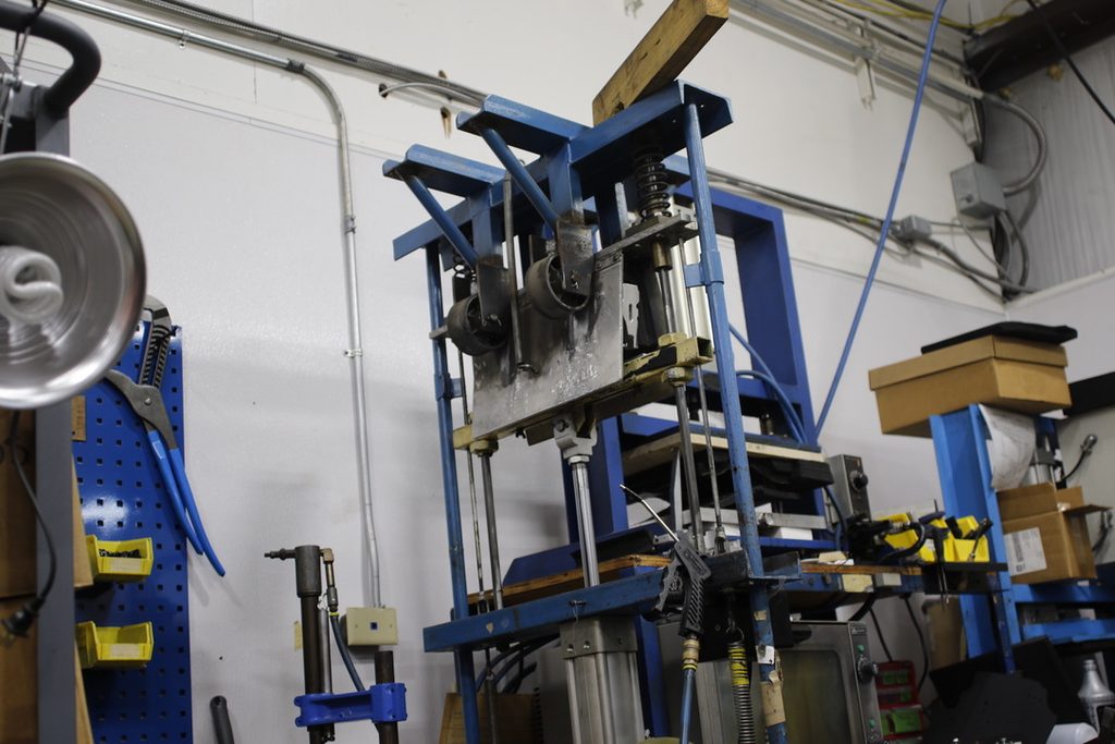 The press used to hold pressure on a holster shell and mandrel during the final forming stage
