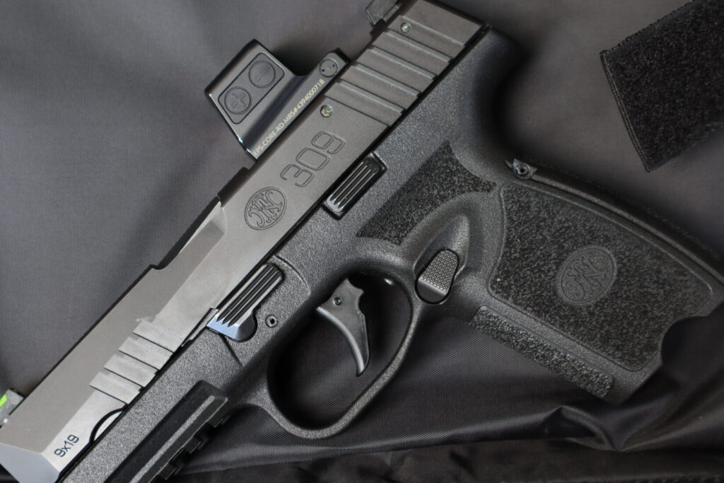 Close-up of the FN 309 MRD's trigger, reversible magazine release, takedown lever, and slide release