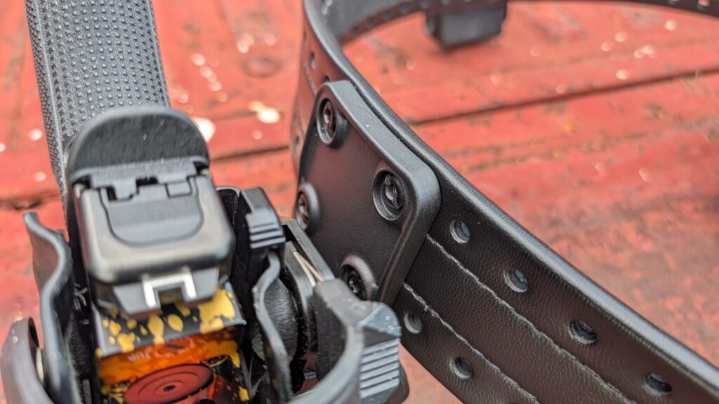 Close-up of a black holster mount secured to the mounting holes of a Safariland HOLLE belt with black screws