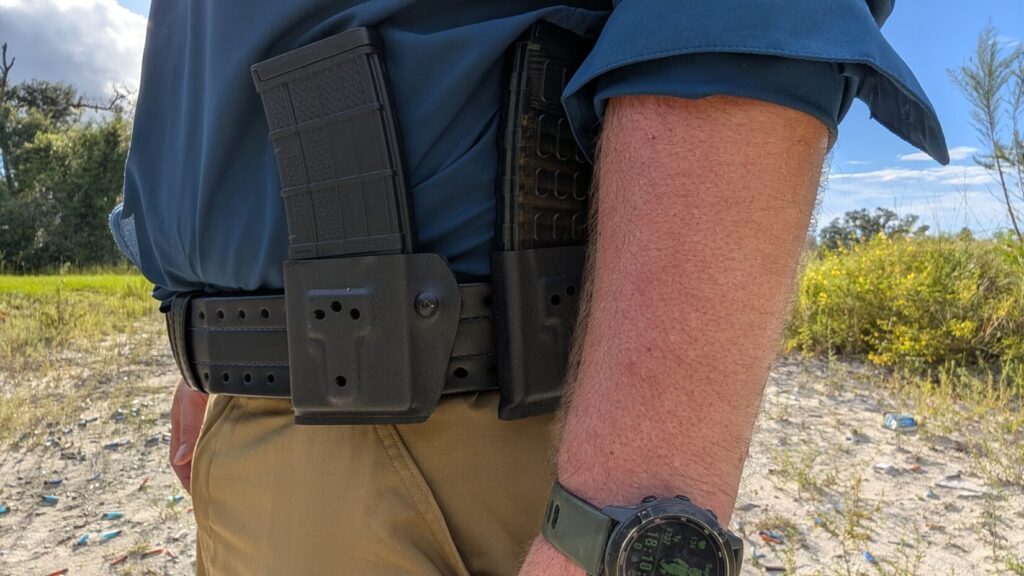 side view of  a black HOLLE belt over khaki pants, showing two black rifle magazine pouches attached to theleft side.