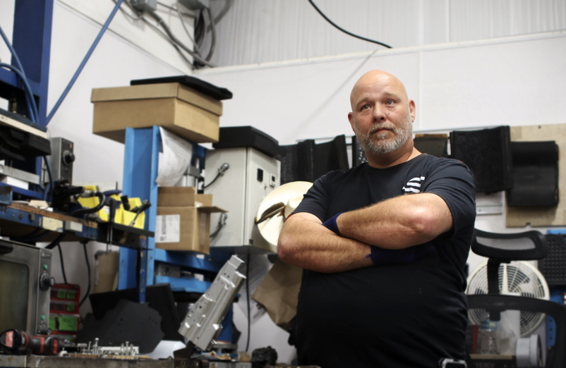 Portrait of Carlos Powell, known as Super Dave, standing arms-crossed in Safariland's Jacksonville holster shop