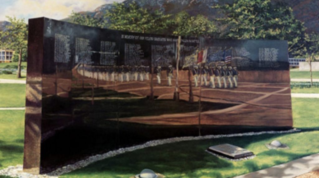 Image of a curved black wall at the Air Force Academy. The names of graduate who were killed in battle are inscribed on it in white. Cadets in blue jackets and white parade pants are reflected in the wall, marching past.