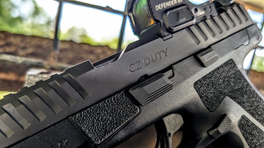 Side profile of a CZ DUTY pistol showing the CZ DUTY slide engraving, serrations, grip texture, and a Vortex Defender-ST red dot