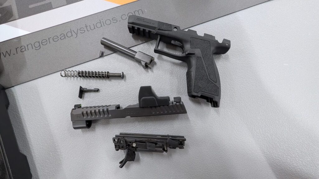 CZ DUTY pistol components laid out, including the grip module, slide with optic, barrel, recoil spring, and trigger assembly